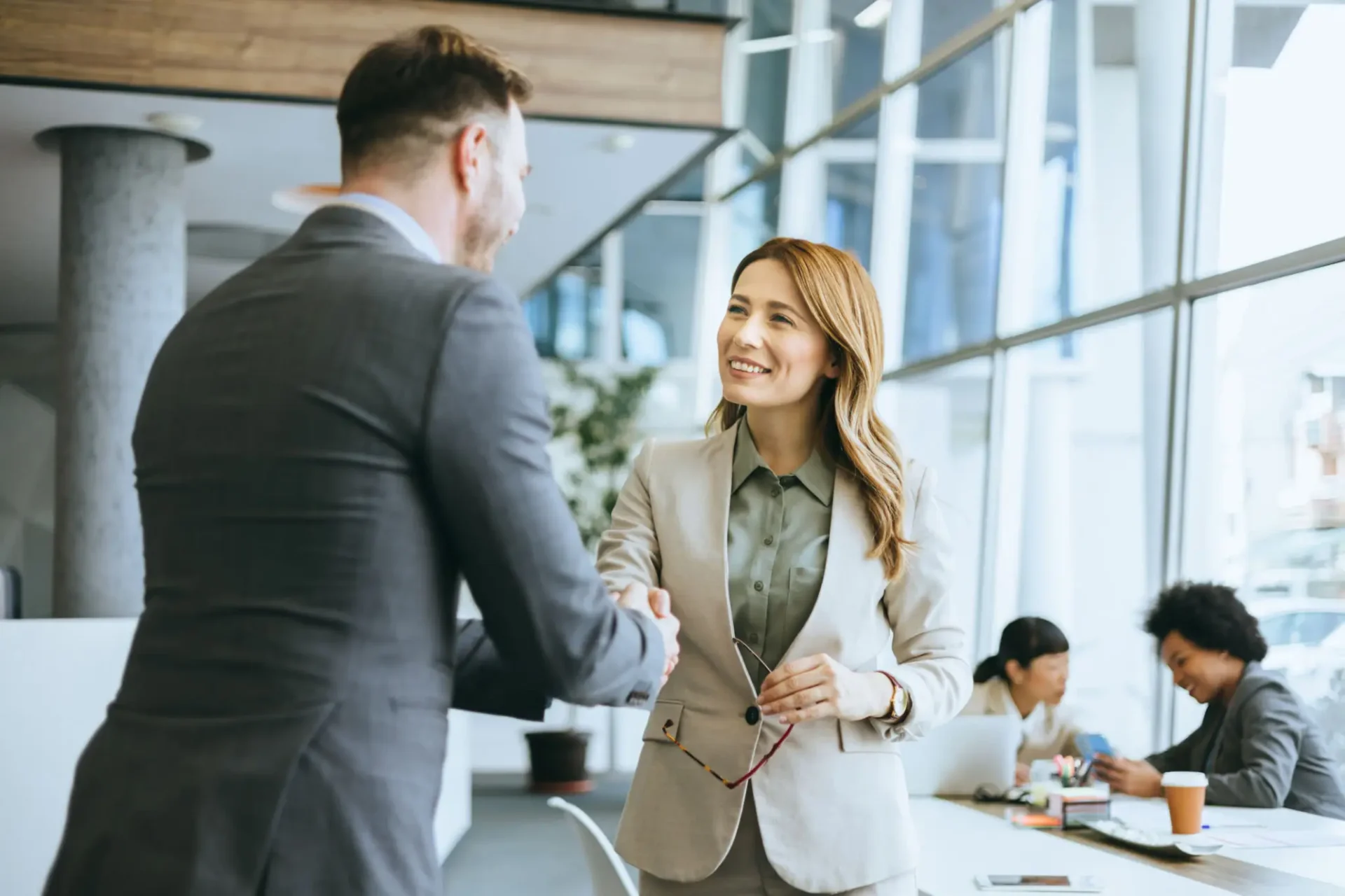 Two professionals shaking hands in a modern office setting.