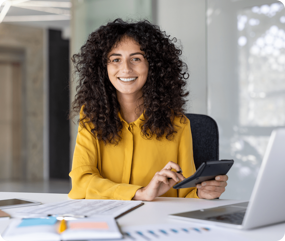 Smiling woman with curly hair working on a tablet in a modern office.
