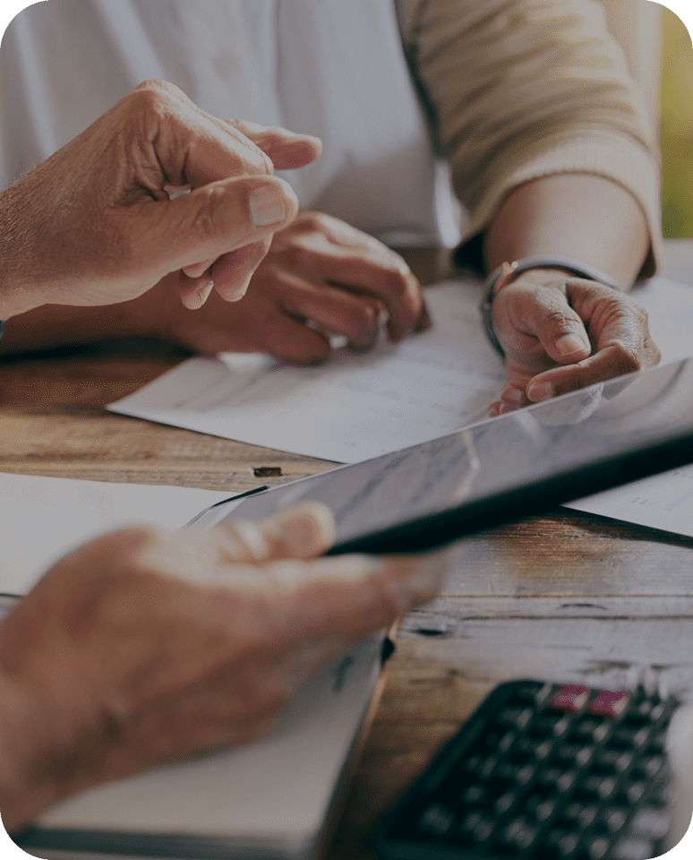 Two people discussing financial documents with a tablet and calculator.